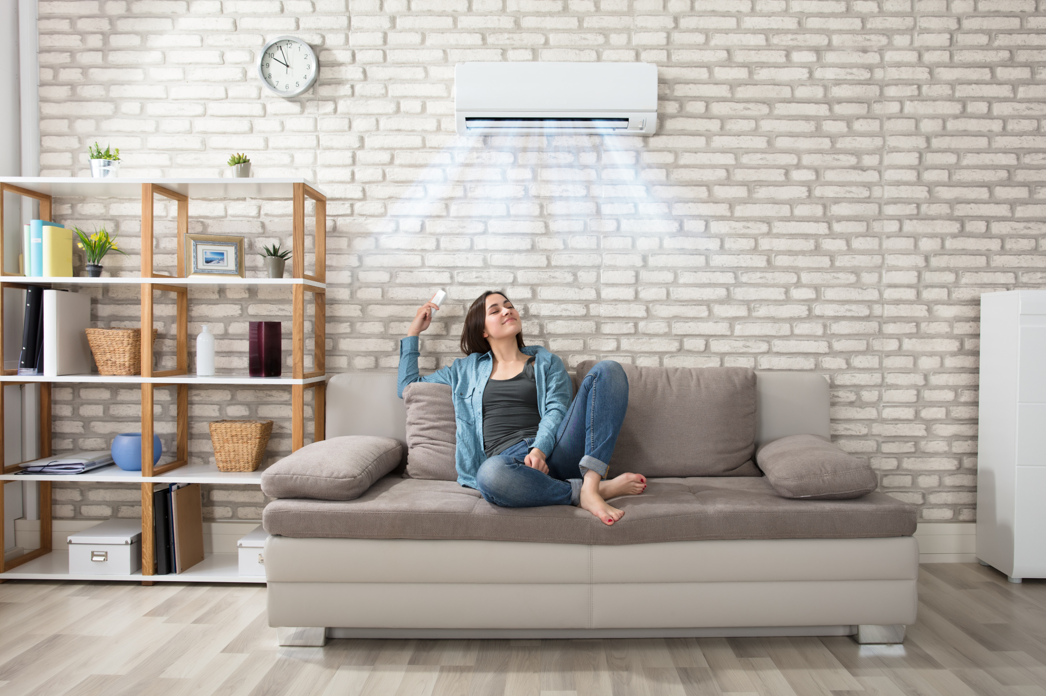 Woman sitting on a sofa in a room with a wall-mounted air conditioner.